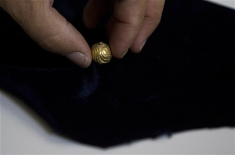 A worker for the IAA, Israel's Antiquities Authority holds a gold bell found in Jerusalem on Sunday. The tiny golden bell preserved for two millennia underneath Jerusalem is ringing again, having been discovered by Israeli archaeologists excavating a Roman-era sewer. 